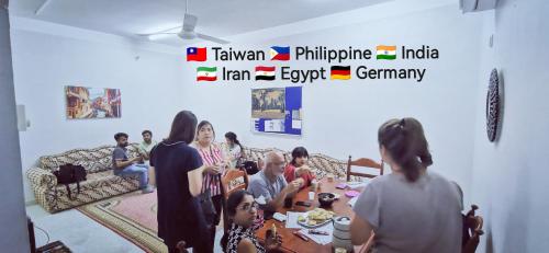 a group of people sitting around a table in a room at 228Hostel in Al Ḩamrāʼ