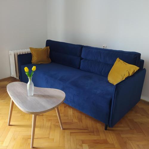 Sofá azul con almohadas amarillas y mesa en Apartament Aksamitny, en Toruń