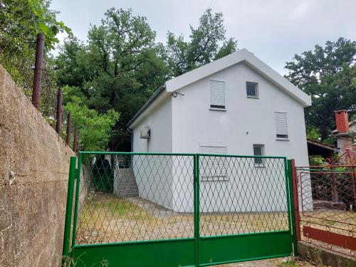 a white house behind a green fence at Apartment Nature in Sutomore