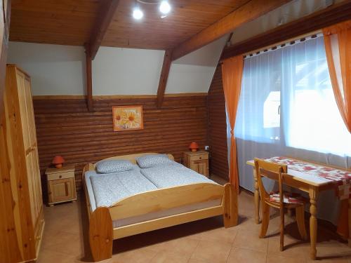 a bedroom with a bed and a table and a window at Őzike Apartmanházak in Bogács