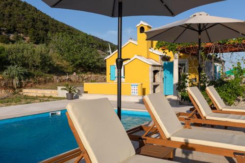 a group of chairs and an umbrella next to a swimming pool at Olive Trees Cottage in Bol