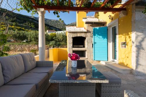 eine Terrasse mit einem Sofa und einem Tisch mit Blumen darauf in der Unterkunft Olive Trees Cottage in Bol