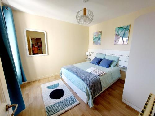 una camera da letto con letto, cuscini blu e specchio di F2 Entre Paris et Eurodisney 5 min à pied gare a Le Perreux-sur-Marne