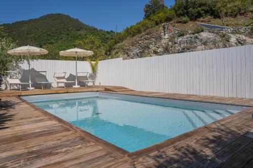 a swimming pool with a wooden deck and a white fence at TIMO - Villa Luisa: con vasca idromassaggio privata in Casarza Ligure