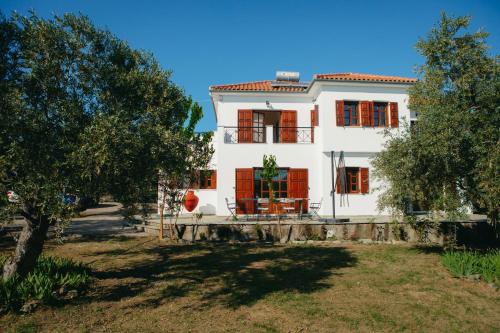a white house with red windows and a tree at Βίλλα Φανούλα Villa Fanoula in Chorto