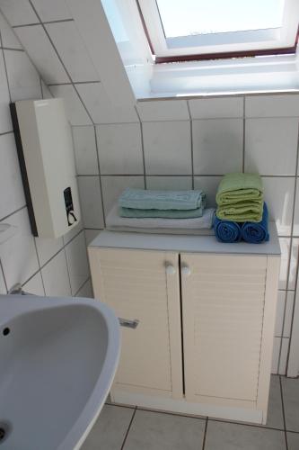 a bathroom with a sink and a window and towels at Haus Seerobbe-Obergeschosswohnung in Fehmarn
