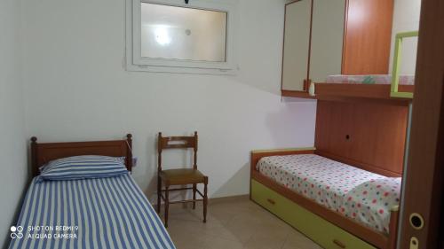 1 dormitorio con 2 camas, silla y espejo en Villa Julia, en Tertenìa