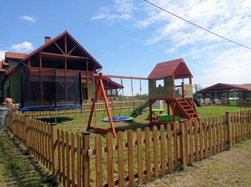 a backyard with a wooden fence and a playground at Dom pod Srebrnym Żurawiem in Wydminy