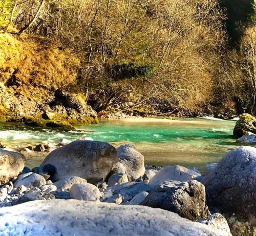 a river with snow covered rocks and the water at Apartma Bovec Center in Bovec