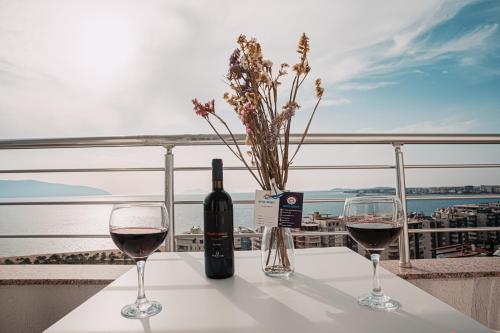 a table with two glasses of wine and a bottle at Hotel SUNSET GL in Vlorë