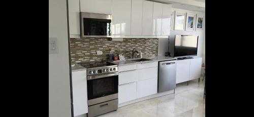 a kitchen with white cabinets and a stove top oven at Yoa’s escape in San Juan