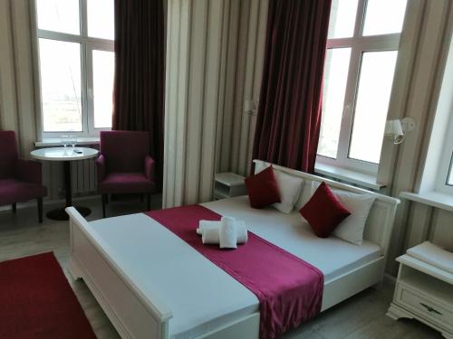 a bedroom with a white bed with red pillows and windows at Apart Hotel Триумф Астаны 22 этаж, Секция 2 in Astana