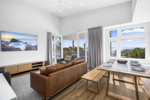 een woonkamer met een bank en een tafel bij Bluehaven Woolgoolga - Brand New, Ocean Views, 200m Stroll to Beach and Restaurants! in Woolgoolga