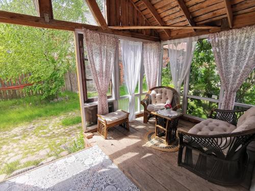 een afgeschermde veranda met stoelen en een open haard bij Mazurskie Klimaty - niezależny, ogrodzony dom in Wydminy