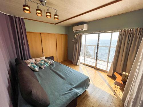 villa chillon في شودوشيما: غرفة نوم بسرير ونافذة كبيرة
