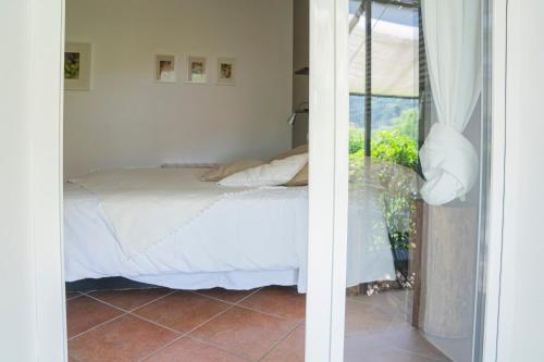 ein Schlafzimmer mit einem weißen Bett und einem Fenster in der Unterkunft MIMOSA - Villa Luisa: Pace, Relax a 2 passi dal mare in Casarza Ligure