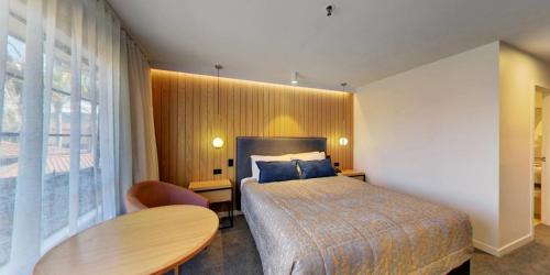 a bedroom with a bed and a table and a window at Distinction Whangarei Hotel & Conference Centre in Whangarei