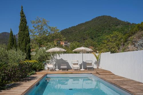 a swimming pool with chairs and umbrellas in a backyard at MIMOSA - Villa Luisa: Pace, Relax a 2 passi dal mare in Casarza Ligure