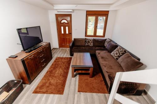 a living room with a couch and a flat screen tv at Bungalow Holiday in Pluzine