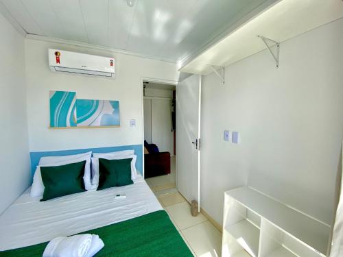 a small room with a bed with green and white pillows at Temporada 737 in Aracaju