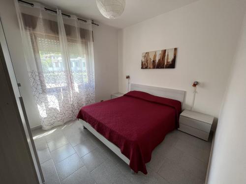 a bedroom with a red bed and a window at Casa Vacanze Tortora in Tortora
