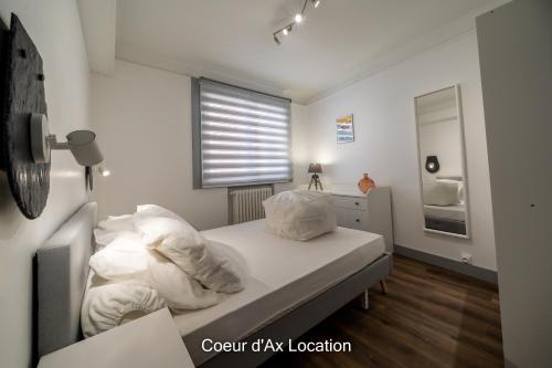 una camera da letto con un letto con cuscini bianchi e una finestra di Cœur d'Ax Location ad Ax-les-Thermes