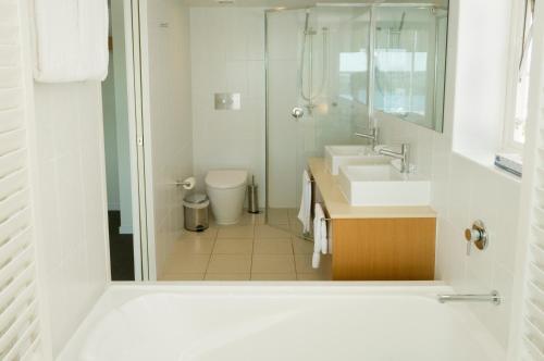 a white bathroom with a sink and a shower at Lanai Riverside Apartments in Mackay