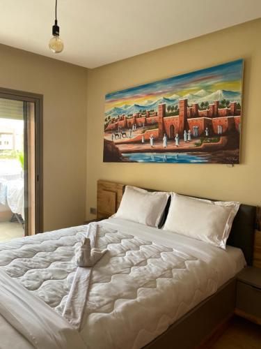 a bedroom with a large white bed with a painting on the wall at Comme a la maison Prestigia Golf acces piscine in Marrakesh