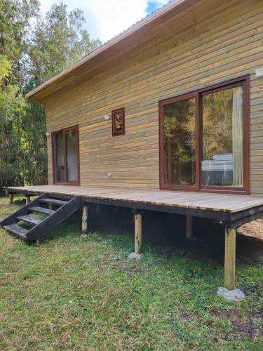 a log cabin with a porch and a large window at El refugio del Volcan Osorno in Puerto Clocker