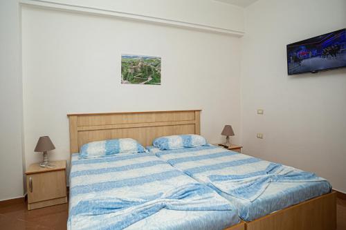 a bedroom with a large bed with a blue blanket at Hotel SUNSET GL in Vlorë