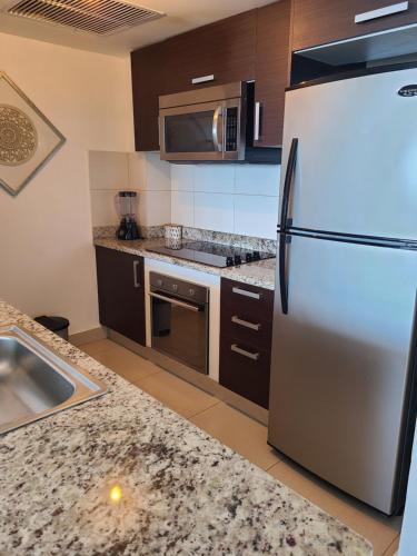 a kitchen with a stainless steel refrigerator and a microwave at Las Olas by Destinos1a in Juan Dolio