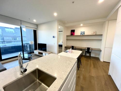 een keuken met een wastafel en een woonkamer bij Readyset Apartments at Marque in Melbourne