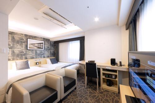 um quarto de hotel com duas camas e uma secretária em Hotel Actel Nagoya Nishiki em Nagoya
