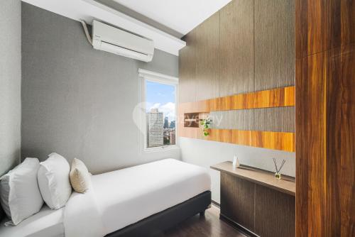 a bedroom with a white bed and a window at PECAN by Kozystay - Sudirman in Jakarta