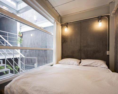 a bedroom with a bed and a window at On the Bed Hostel in Bangkok