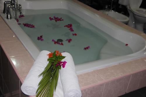 a bath tub with towels and flowers in it at The Norfolk Heritage Airport Villa in Katunayake