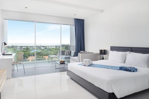 a bedroom with a white bed and a large window at Mida De Sea Hua Hin - SHA PLUS in Cha Am