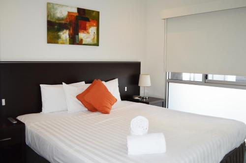 a bedroom with a large white bed with orange pillows at Adara St Kilda in Melbourne