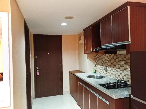 a kitchen with wooden cabinets and a sink at Cozy The H Residence Cawang by Bonzela Property in Jakarta
