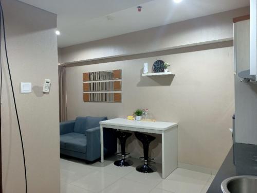 a living room with a table and a blue couch at Cozy The H Residence Cawang by Bonzela Property in Jakarta