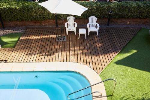 two chairs and an umbrella next to a swimming pool at Hotel Termas Day in Termas del Daymán