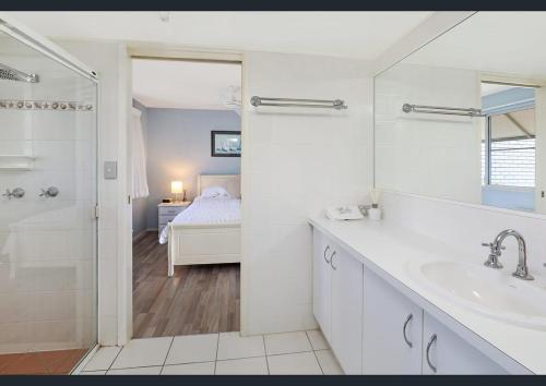 a white bathroom with a sink and a shower at Excellsior Apartments in Mooloolaba