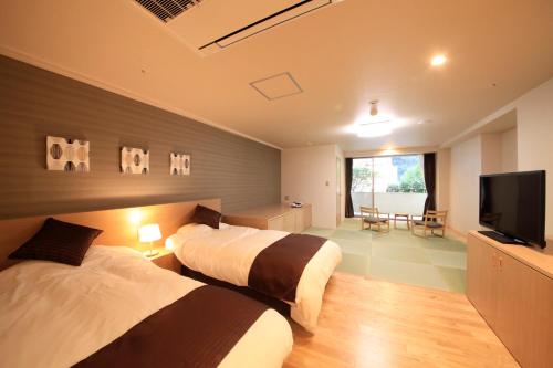 a hotel room with two beds and a flat screen tv at Hakone Pax Yoshino in Hakone