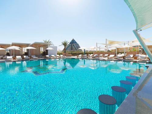a large swimming pool with chairs and umbrellas at Sofitel Dubai The Obelisk in Dubai