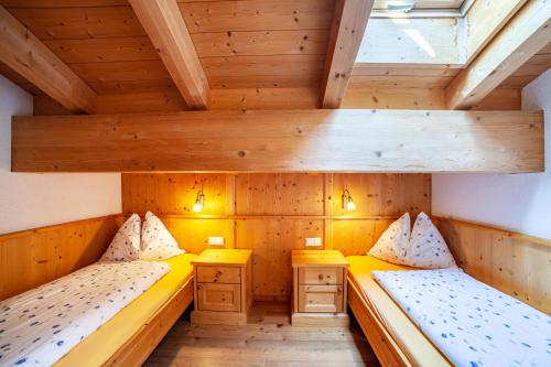 Duas camas num pequeno quarto com tectos em madeira em Hof am Schloss Apartement Zirm em Montechiaro