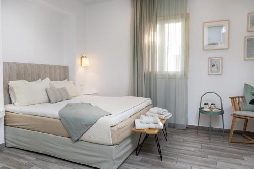 a white bedroom with a bed and a window at Korali Hotel in Naxos Chora