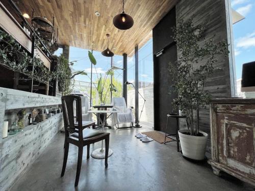 a room with a chair and a table and some plants at Guest House maison de stuffmarket in Takamatsu