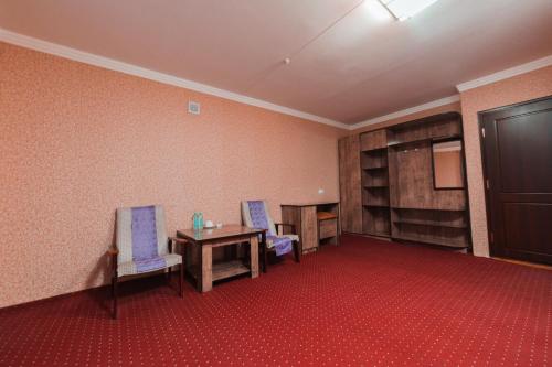 a room with two chairs and a table and shelves at Reikartz Kokand in Kokand