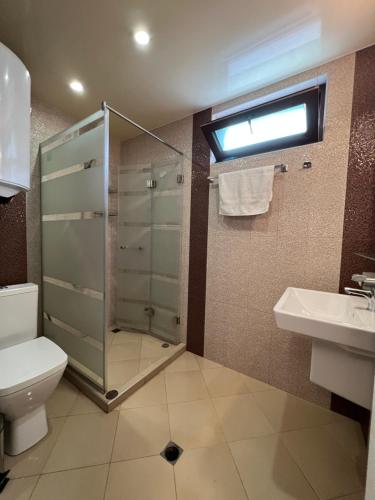 a bathroom with a shower and a toilet and a sink at TEA Apartments in Pomorie