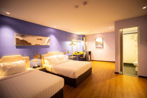 1 Schlafzimmer mit 2 Betten und einer lila Wand in der Unterkunft Le Embassy Hotel Georgetown in George Town